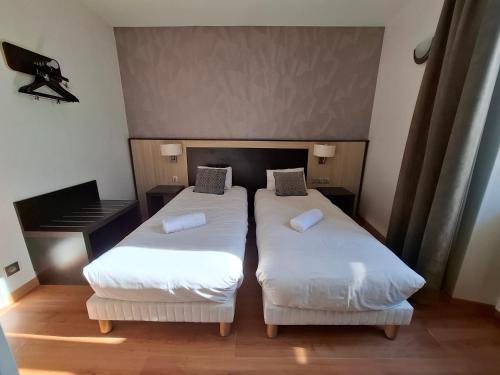 two twin beds in a room with a piano at Hotel Le Coureau in Saint-Trojan-les-Bains