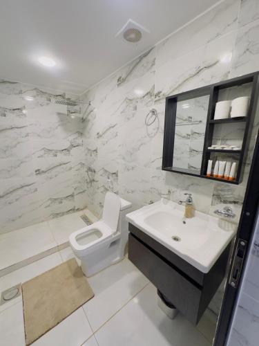 a white bathroom with a toilet and a sink at RUM FLORAA LUXURY CAMp in Wadi Rum