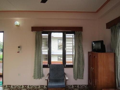 a room with a window with a chair and a television at New Annapurna Guest House in Pokhara
