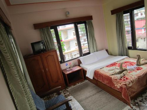 a bedroom with a bed and a dresser and windows at New Annapurna Guest House in Pokhara