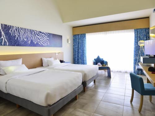 a hotel room with two beds and a desk at Novotel Marsa Alam Beach Resort in Quseir