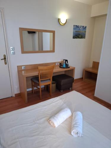 a bedroom with a bed with a desk and a chair at Hotel Le Coureau in Saint-Trojan-les-Bains