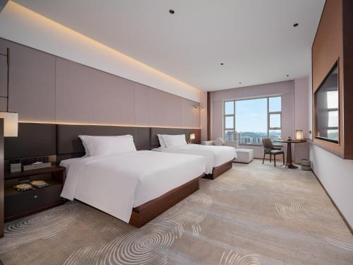a hotel room with two beds and a desk at SINOKAI International Hotel in Maqifa