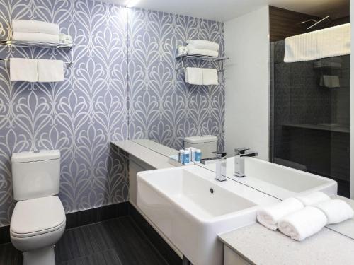 a bathroom with a white sink and a toilet at Novotel New Plymouth Taranaki in New Plymouth