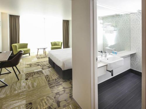 a hotel room with a bed and a sink and a desk at Novotel New Plymouth Taranaki in New Plymouth