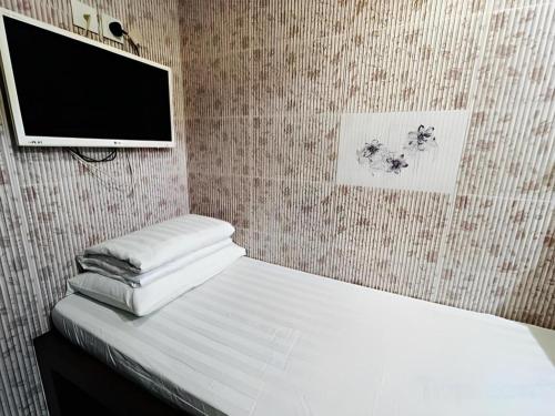 a bedroom with a bed and a flat screen tv at New Mong Kok Guest House in Hong Kong