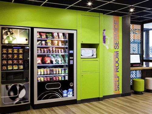 a store with a green wall with a soda refrigerator at ibis budget Grigny Centre in Grigny