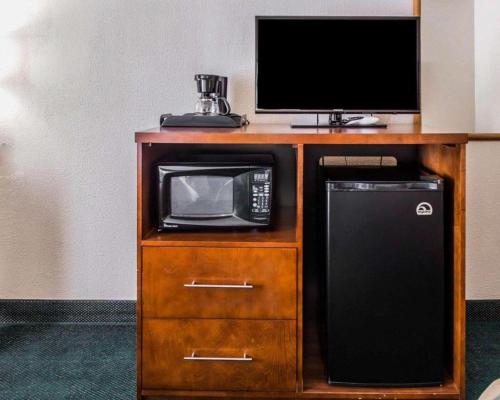 a microwave and a television on a wooden cabinet at Quality Inn Waynesburg - Morrisville in Waynesburg