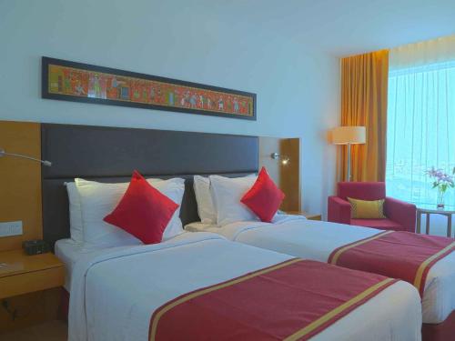 two beds in a hotel room with red and white pillows at Mercure Hyderabad KCP Banjara Hills, An Accor Hotel in Hyderabad