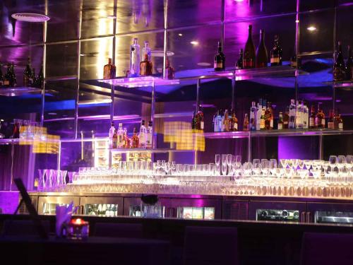 a bar filled with lots of glasses and purple lights at Mercure Hyderabad KCP Banjara Hills, An Accor Hotel in Hyderabad