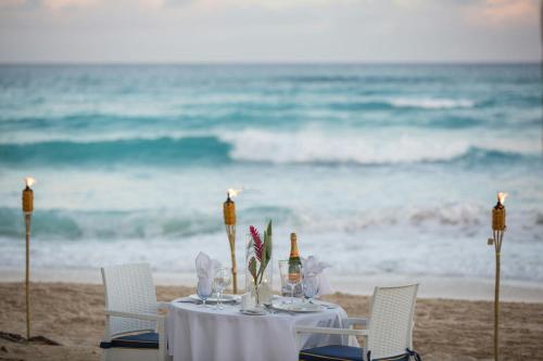 a table with wine glasses and candles on the beach at Turtle Beach, a Tribute Portfolio All Inclusive Hotel in Christ Church