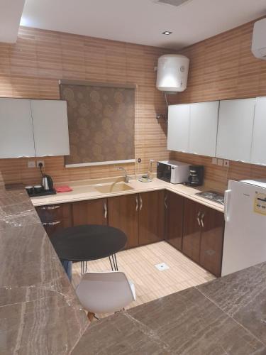 a kitchen with wooden cabinets and a sink and a chair at إيفان للشقق المخدومة المروج in Riyadh