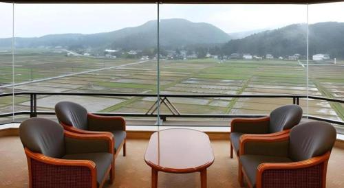 a room with chairs and a table and a large window at Shiratamano Yu Kahou in Shibata