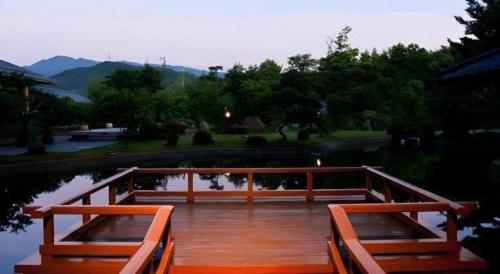 a wooden deck with two benches on a body of water at Shiratamano Yu Kahou in Shibata