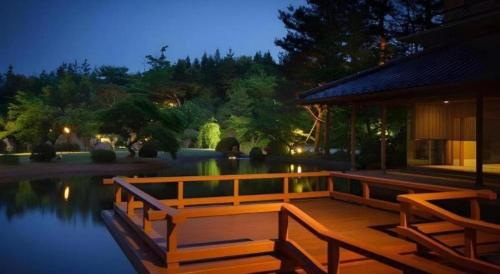 a wooden deck with two benches next to a lake at Shiratamano Yu Kahou in Shibata