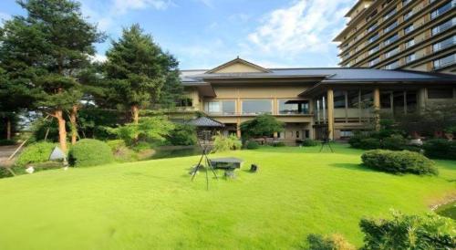 a large house with a green lawn in front of it at Shiratamano Yu Kahou in Shibata