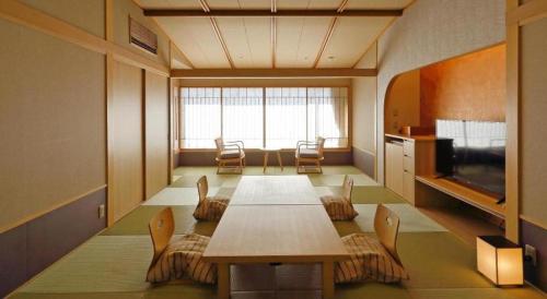 a room with a table and chairs and a television at Tsukino Sumika Atami Juraku Hotel in Atami