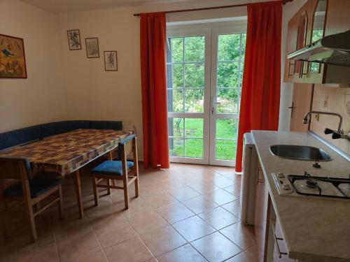 cocina con mesa y cocina con cortinas rojas en Apartman Janky 299, en Trutnov