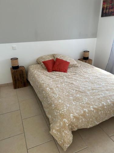 Cottage a Vidauban في فيداوبان: غرفة نوم بها سرير عليه وسادتان حمراوان