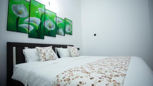 a bedroom with a white bed with four paintings on the wall at Hotel Magdalina Lagoon in Negombo