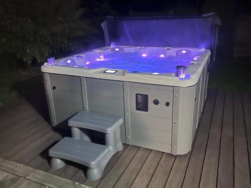 un jacuzzi avec un banc et un tabouret dans l'établissement Chalet Vertpheny Spa & Terrasse à 500m du Lac de Gérardmer, à Gérardmer