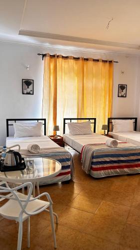 two beds in a room with a table and chairs at Kindo Kicha Farmhouse in Moshi