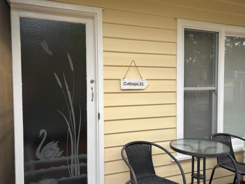 a front door of a house with a table and chairs at Cottage 32 in Lakes Entrance