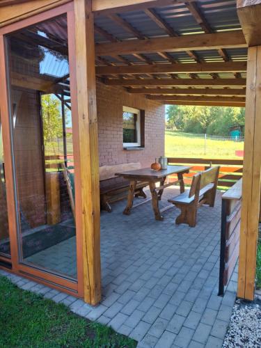 a patio with a wooden pergola and a table and bench at Domek nad Stawem in Istebna