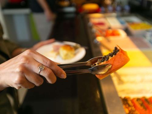 a person holding a spoon and a plate of food at ibis budget RJ Copacabana in Rio de Janeiro