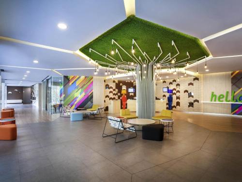 a lobby with a green wall and tables and chairs at Ibis Styles Jakarta Sunter in Jakarta
