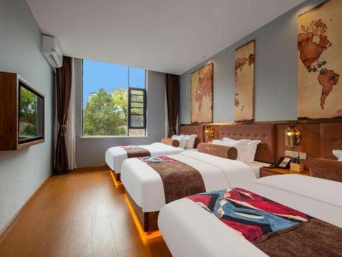 a hotel room with three beds and a large window at James Joyce Coffetel·Lijiang Old Town Centeral in Lijiang