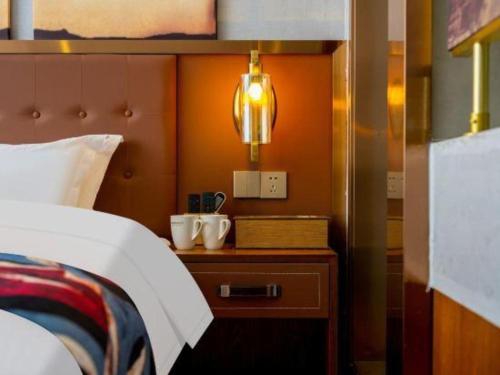 a hotel room with a bed and a nightstand with a bed sqor at James Joyce Coffetel·Lijiang Old Town Centeral in Lijiang