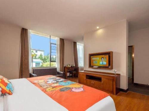 a hotel room with a bed and a flat screen tv at James Joyce Coffetel·Lijiang Old Town Centeral in Lijiang