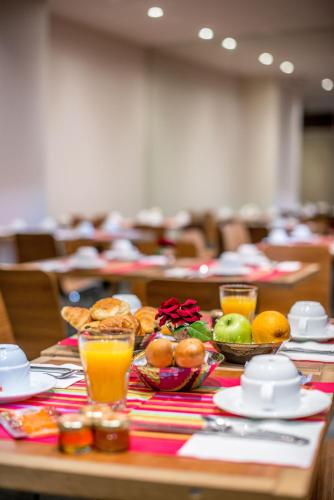 パリにあるアートホテル　エッフェルの食べ物の皿とオレンジジュースのグラスが置かれたテーブル