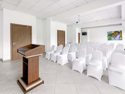 a lecture hall with white chairs and a podium at Ibis Styles Accra Airport in Accra