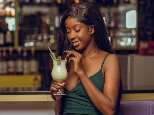 a woman is smiling while holding a drink at Ibis Styles Accra Airport in Accra