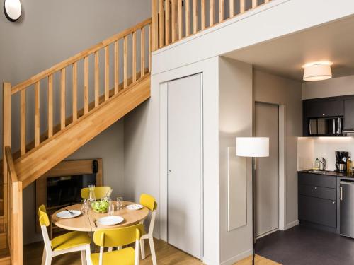 a dining room with a table and yellow chairs at Aparthotel Adagio access Colombes La Défense in Colombes