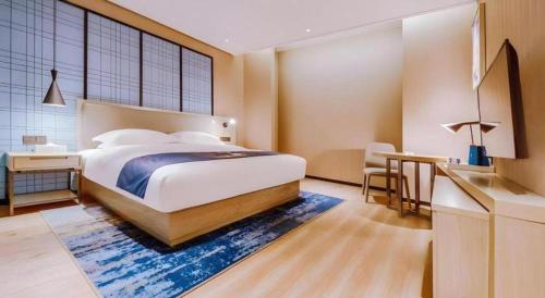 a bedroom with a bed and a table and a desk at Echarm Hotel Guizhou Xingyi Jushan Avenue in Xiawutun