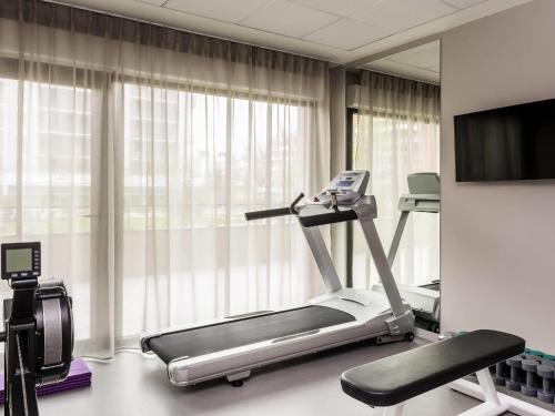 a gym with a treadmill and a flat screen tv at Aparthotel Adagio access Colombes La Défense in Colombes