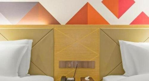 a room with two beds and a colorful wall at Borrman Hotel Zhuhai Gongbei Port Fuhuali Light Rail in Zhuhai