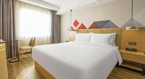 a large white bed in a hotel room at Borrman Hotel Zhuhai Gongbei Port Fuhuali Light Rail in Zhuhai