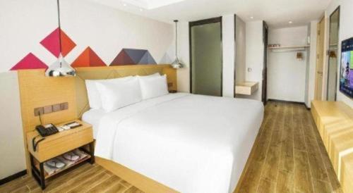 a bedroom with a large white bed and a telephone at Borrman Hotel Zhuhai Gongbei Port Fuhuali Light Rail in Zhuhai