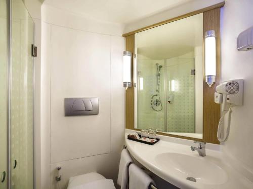 a bathroom with a sink and a toilet and a mirror at Ibis Manado City Center Boulevard in Manado