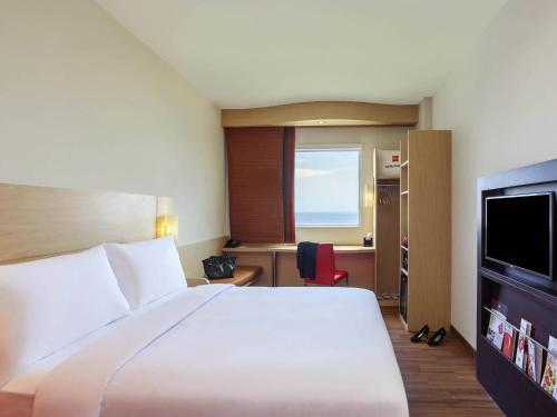 a hotel room with a bed and a television at Ibis Manado City Center Boulevard in Manado
