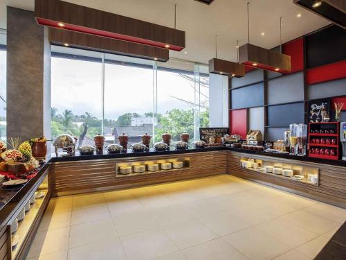 a restaurant with a bar with a counter with food at Ibis Manado City Center Boulevard in Manado