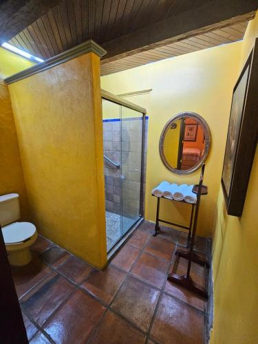 a bathroom with a shower and a toilet and a mirror at Hotel Art Gallery Casona de los Milagros in Colima