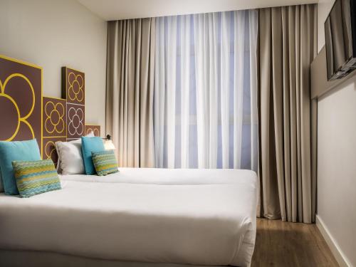a bedroom with a large white bed in front of a window at ibis Styles Barcelona Centre in Barcelona