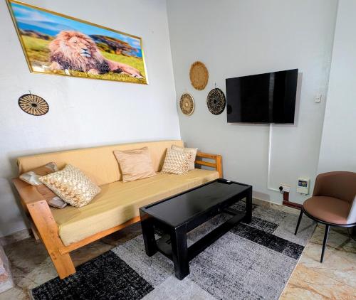 a living room with a couch and a tv at Oslo Gardens Airport in Entebbe
