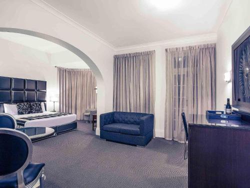 a hotel room with a bed and a blue chair at Mercure Maitland Monte Pio in Maitland