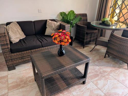 a living room with a couch and a table with flowers at Oslo Gardens Airport in Entebbe